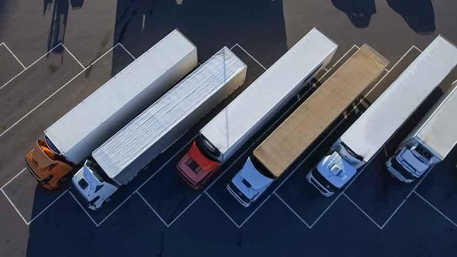 Questa immagine mostra dall'alto degli autocarri all'interno di un parcheggio.